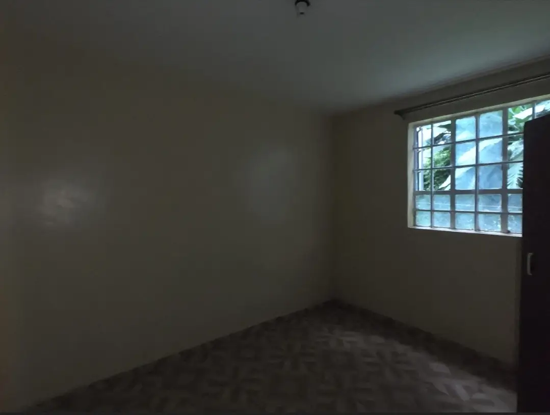 Empty bedroom with large window and dark flooring