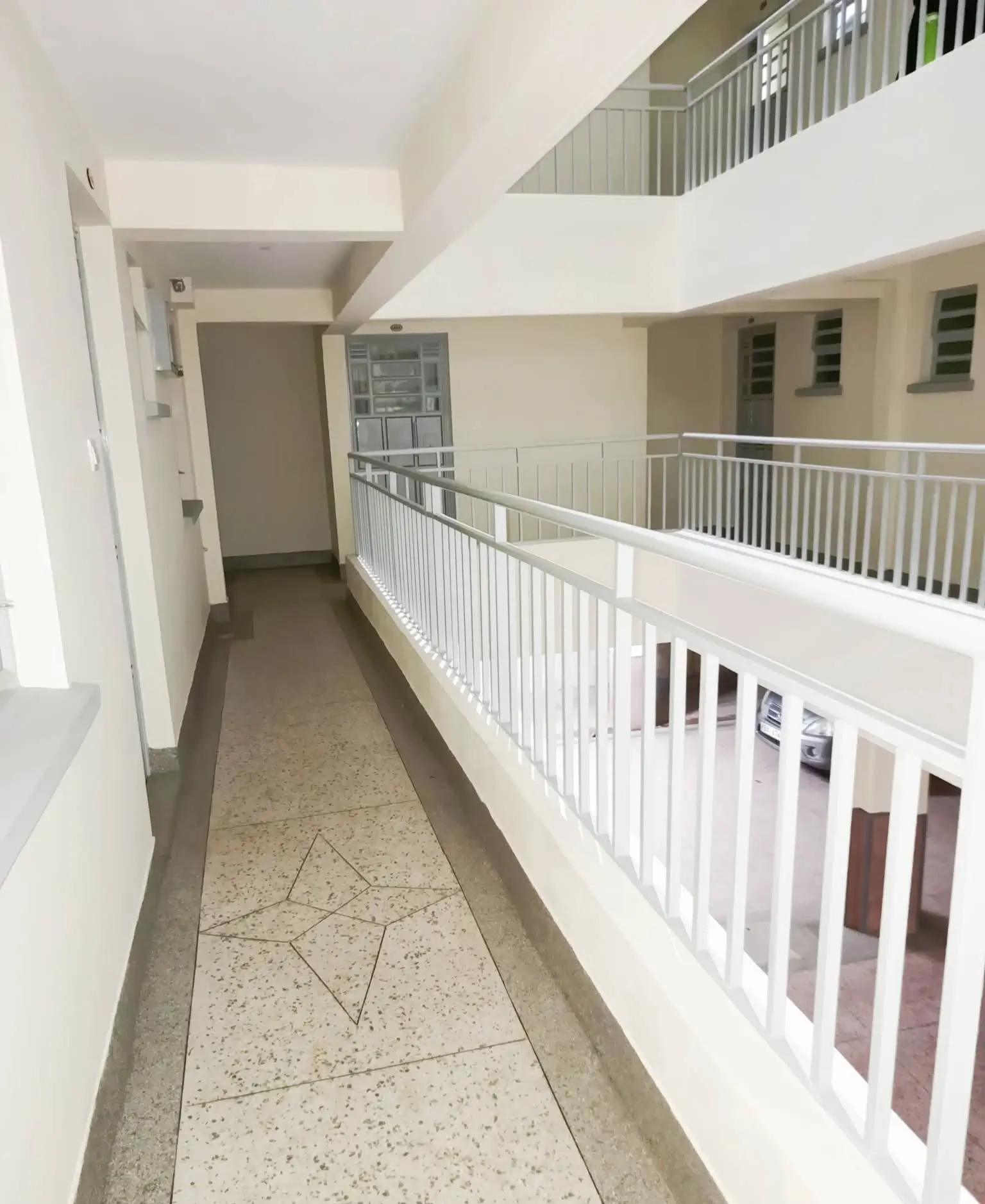Multi-level interior corridor with white railings and terrazzo flooring