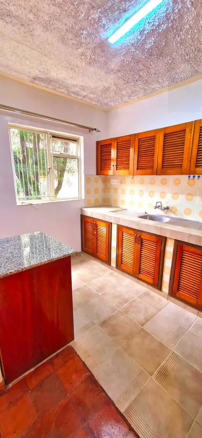 Compact kitchen with wooden cabinets and red island counter