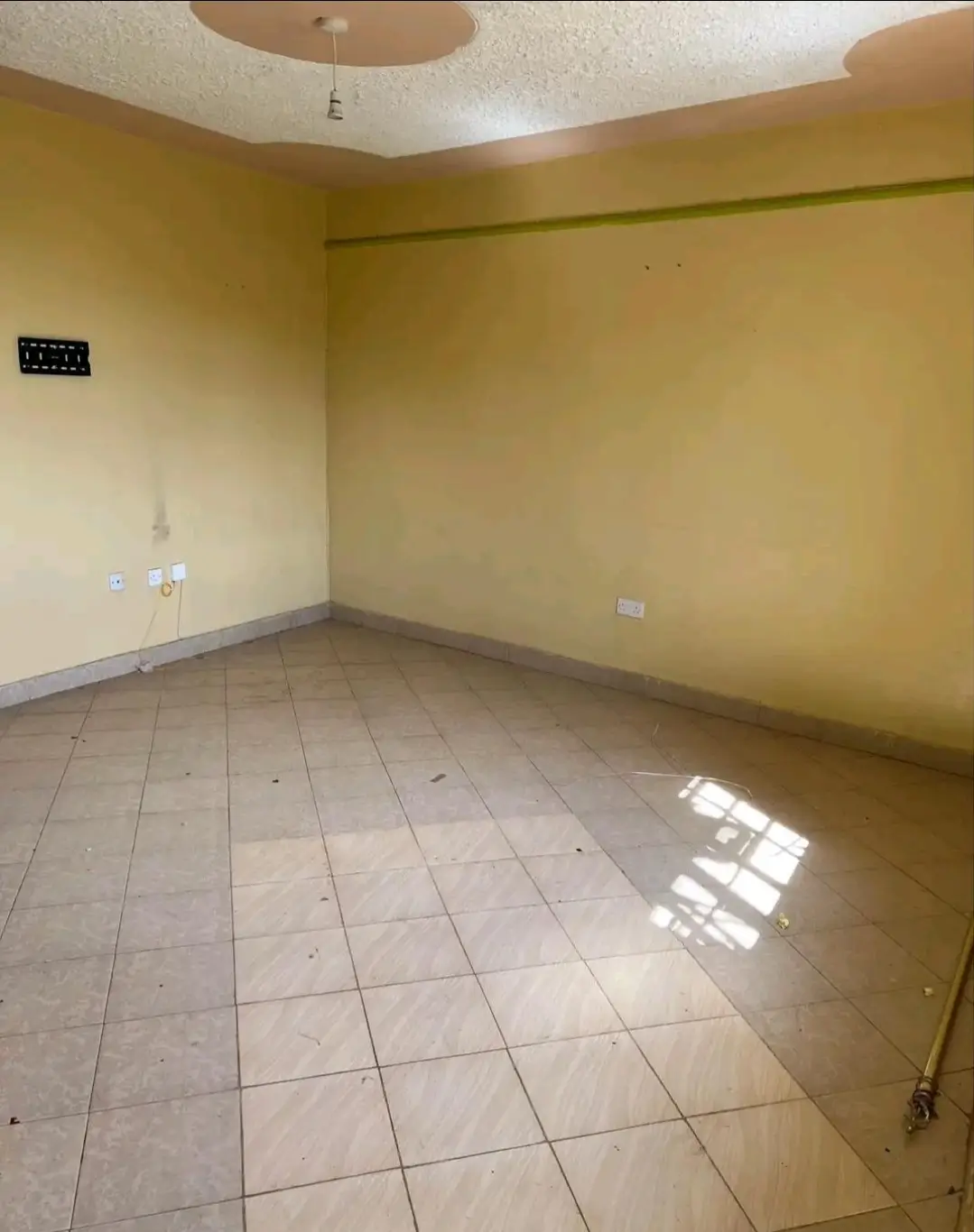 Empty living room with yellow walls and tiled flooring