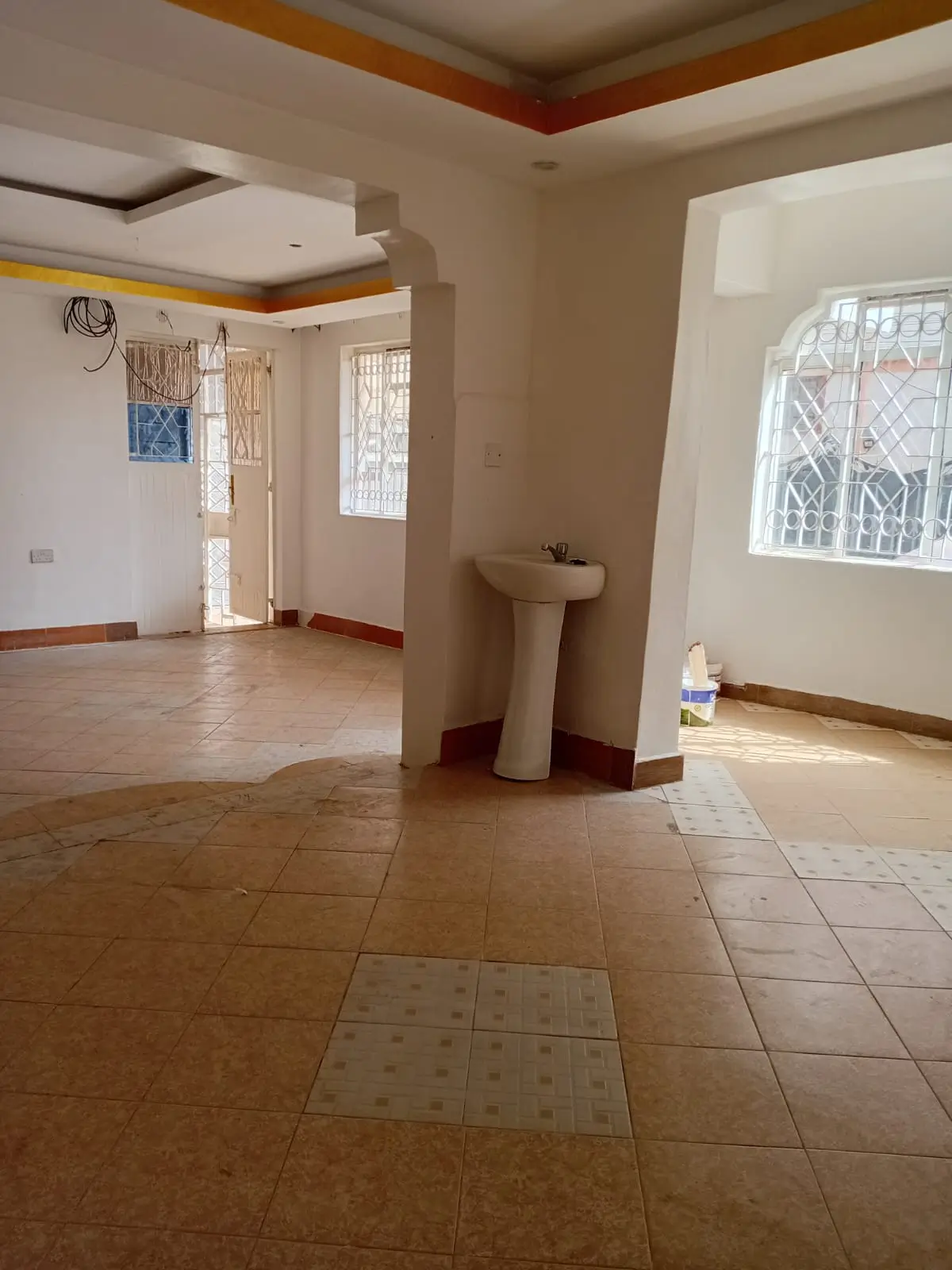 Open-plan living space with pedestal sink and tiled flooring
