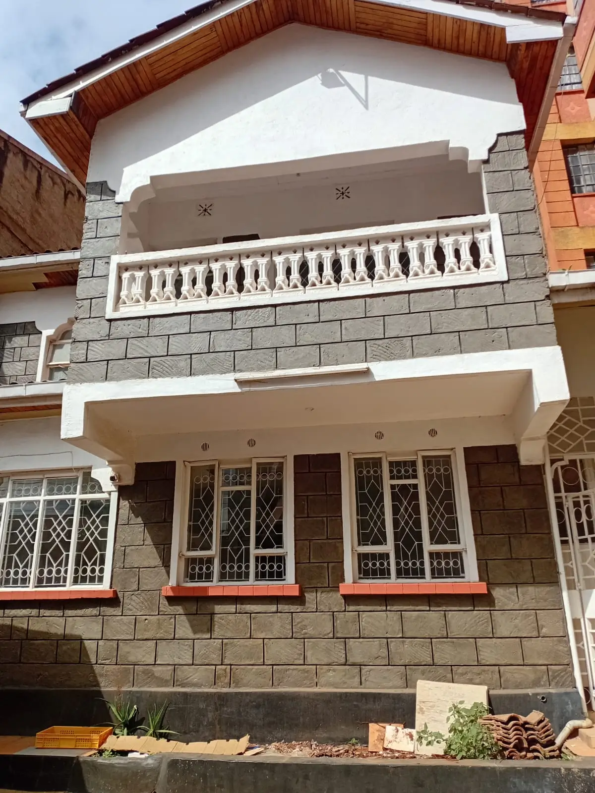 Two-story residential building facade with white balustrade and stone cladding