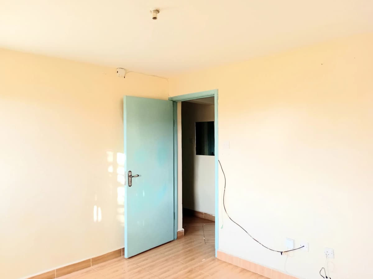 Empty bedroom with turquoise door and wooden flooring