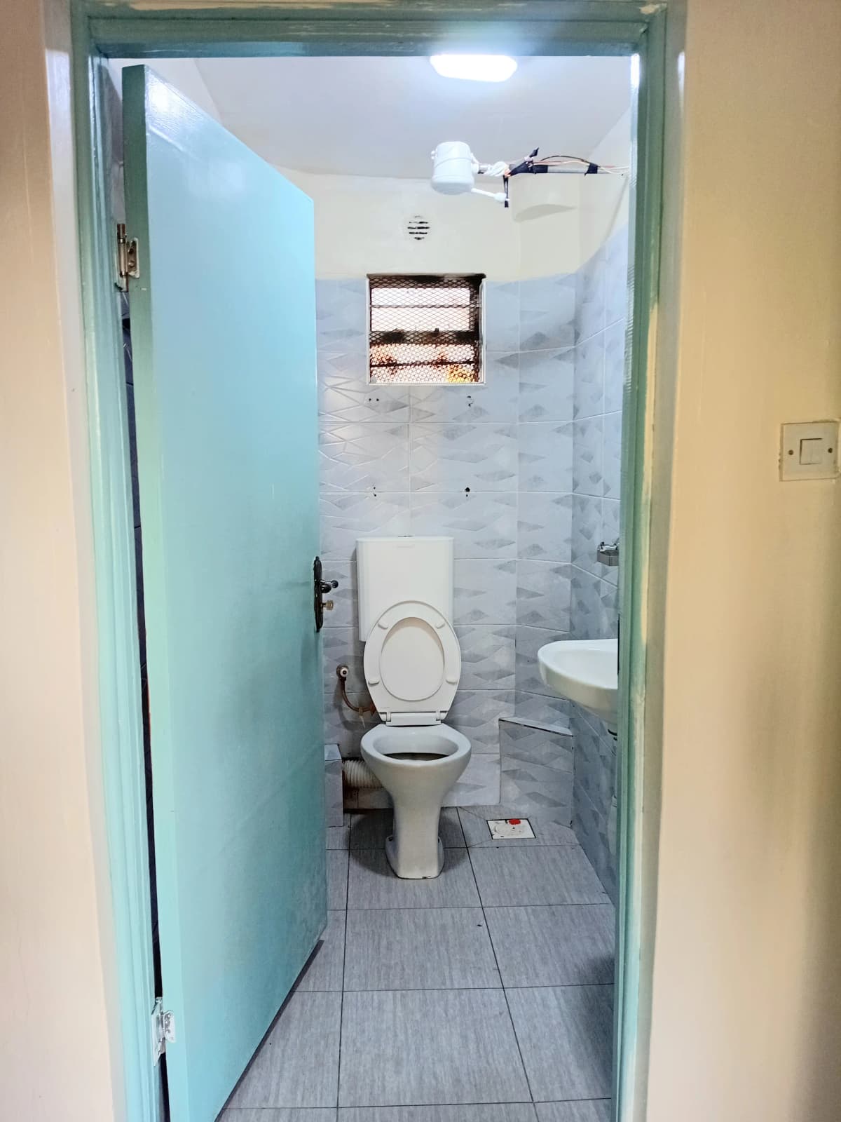 Compact bathroom with toilet, sink, and tiled shower area