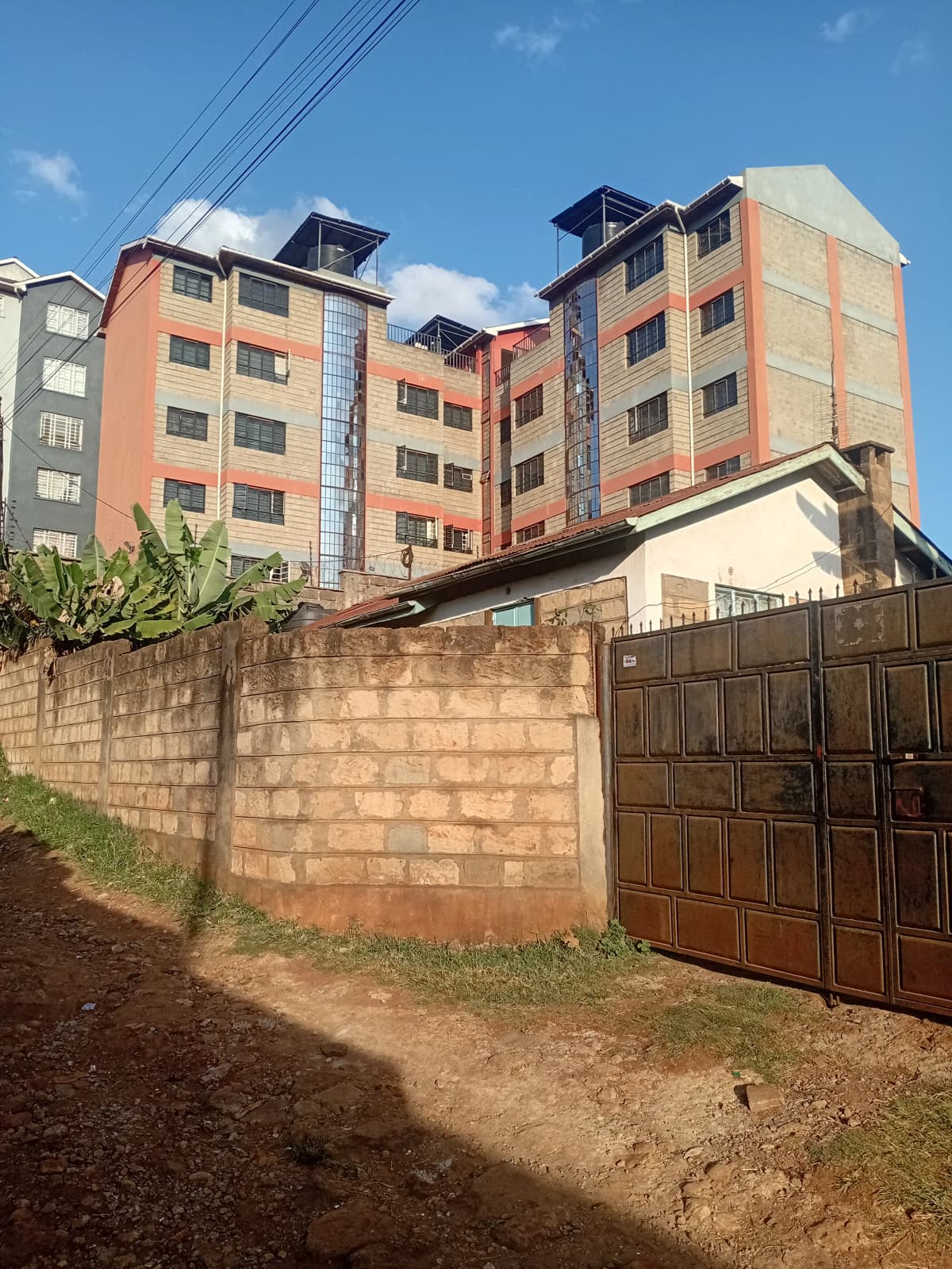 Multi-story residential building with perimeter wall and gate entrance