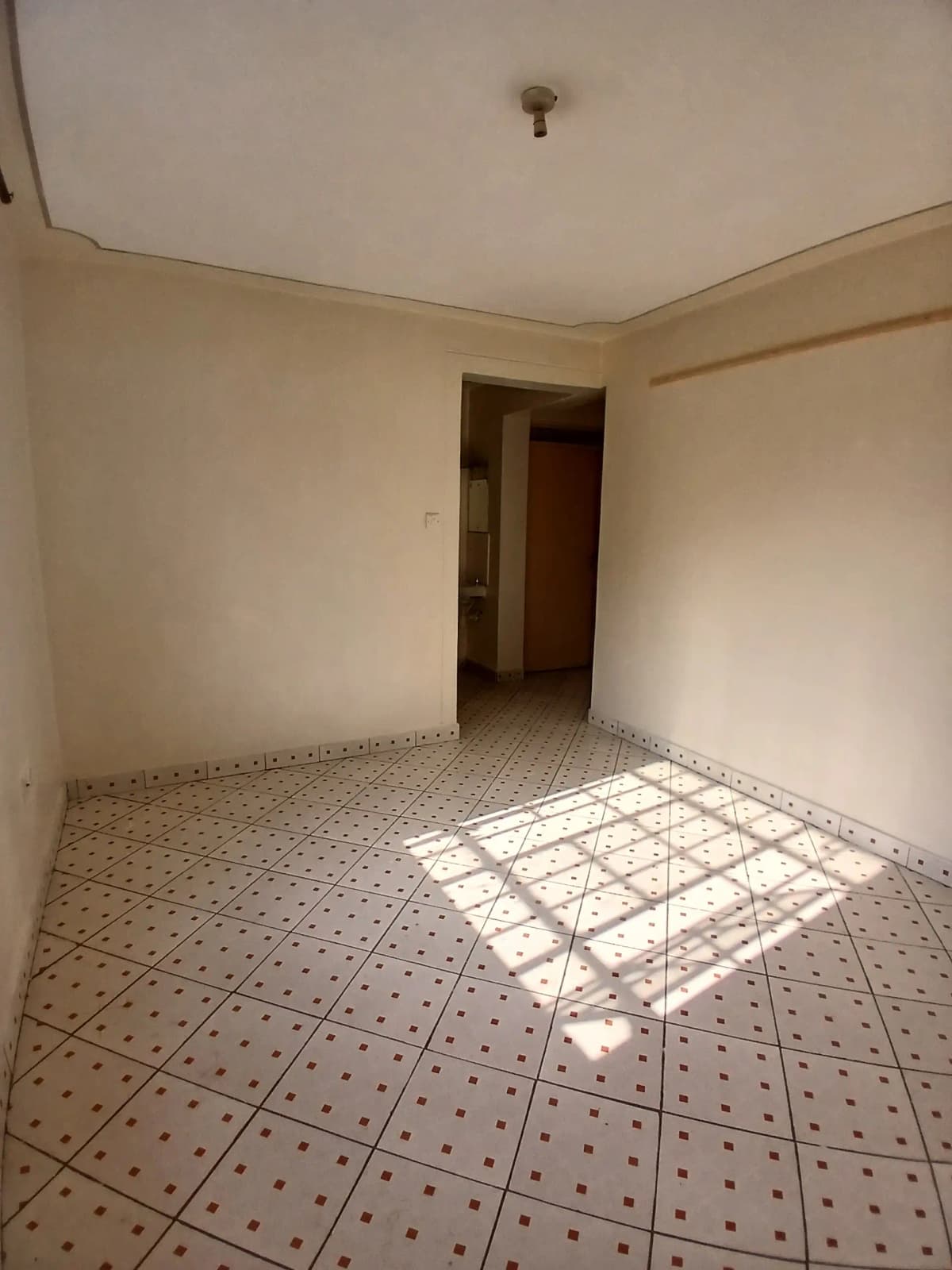 Empty bedroom with patterned tile flooring and natural light
