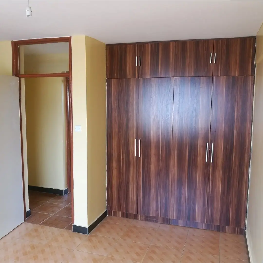 Spacious bedroom with built-in wooden wardrobe and doorway