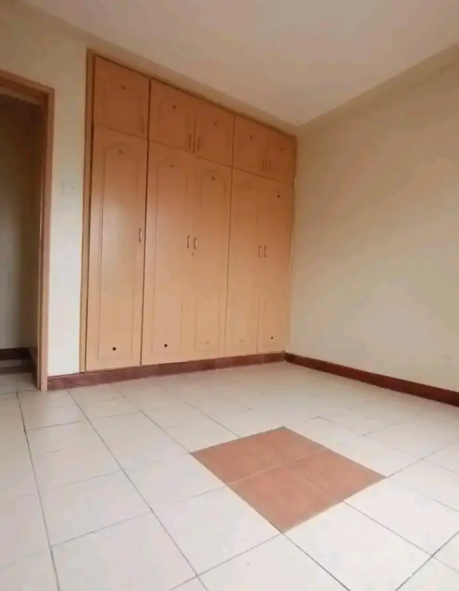 Spacious bedroom with wooden built-in wardrobe and tiled flooring
