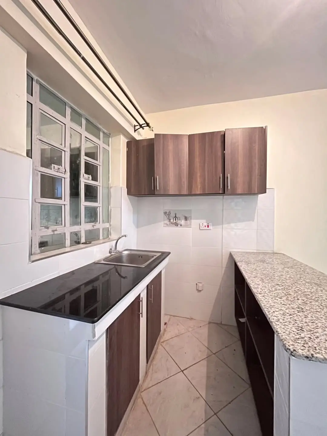 Galley kitchen with dark wood cabinets and granite countertops.
