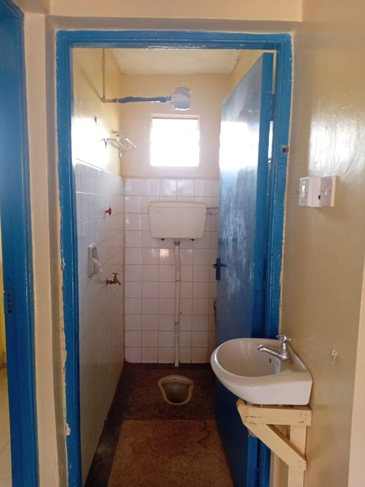 Narrow bathroom with white tiles, sink, and blue door frame