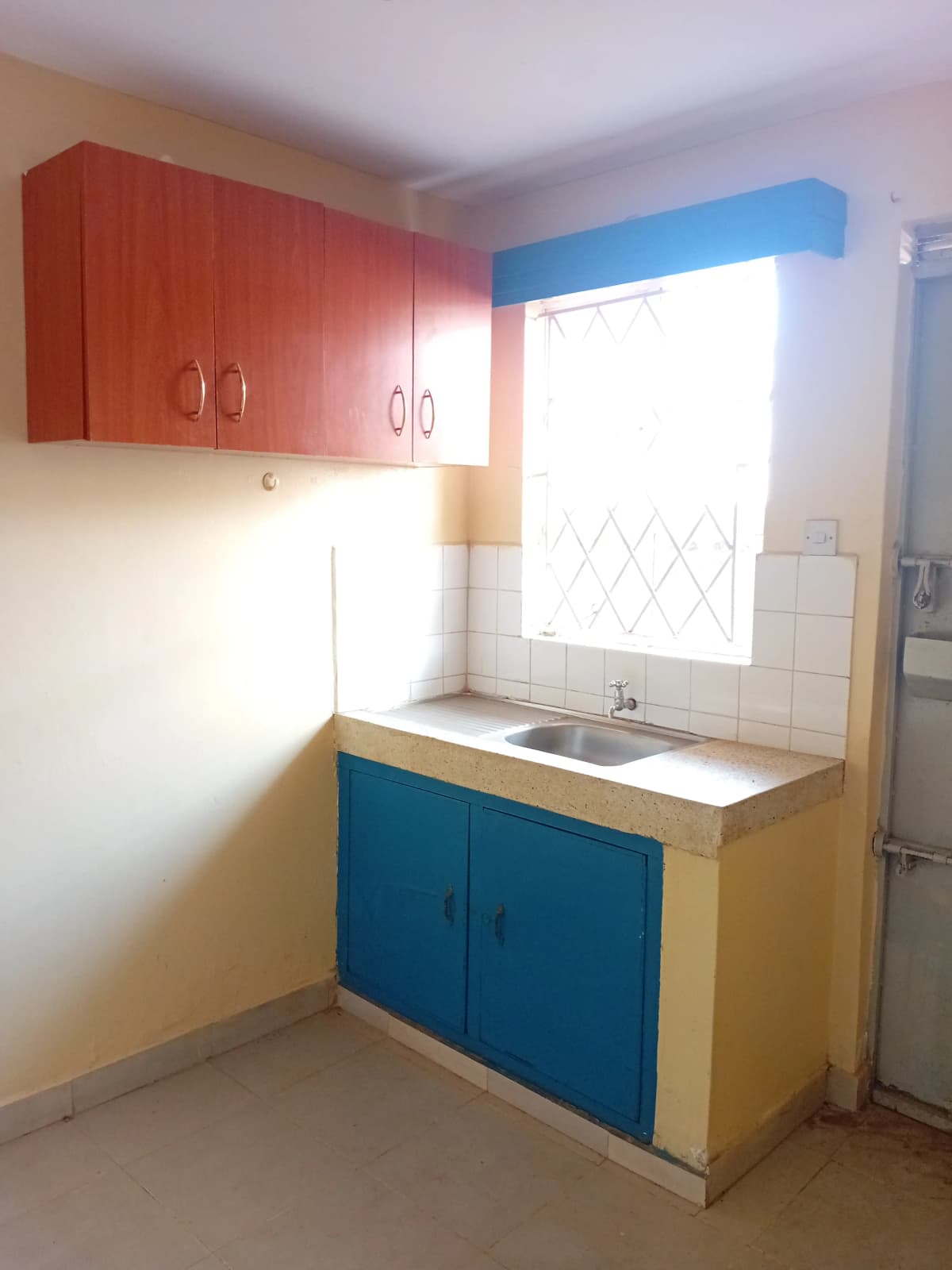 Compact kitchen with red upper cabinets, blue lower storage, sink