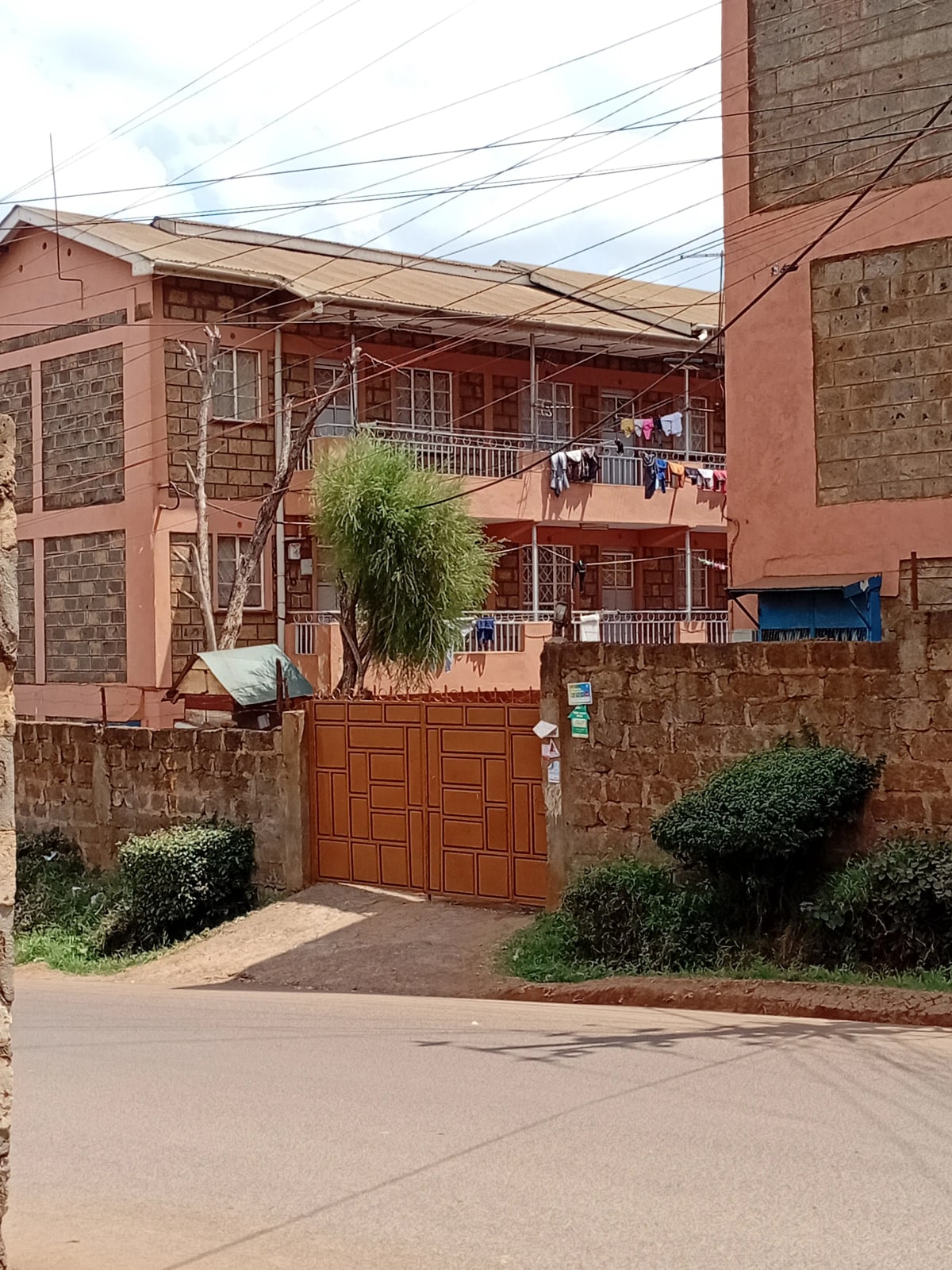 Two-story residential building with wooden gate and compound entrance