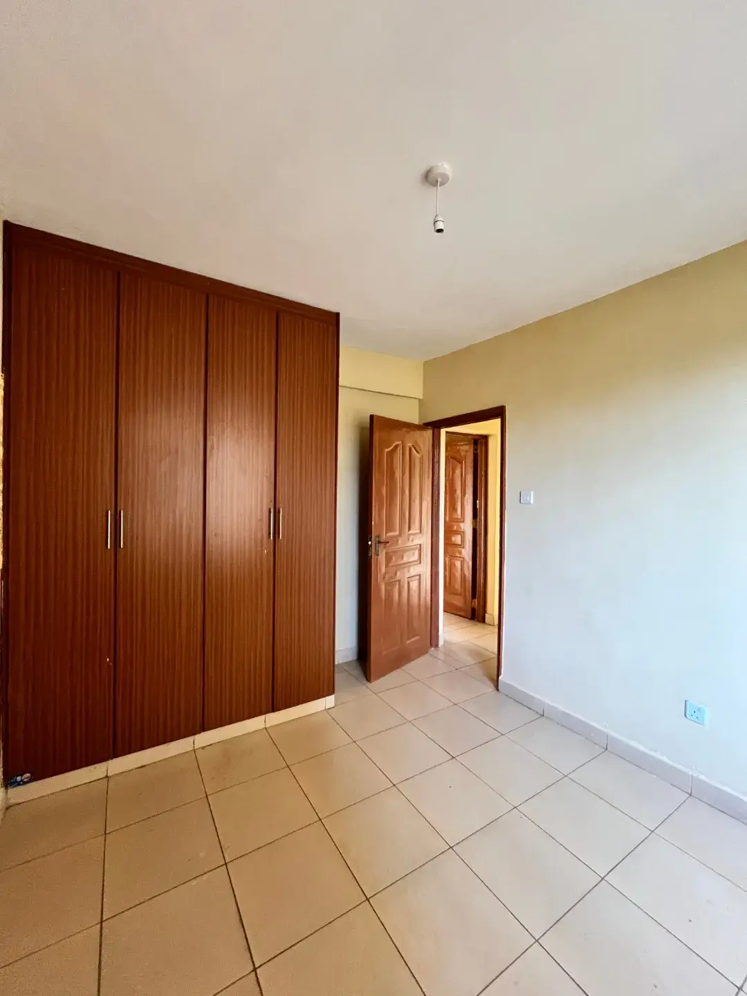 Spacious bedroom with wooden wardrobe and tiled flooring