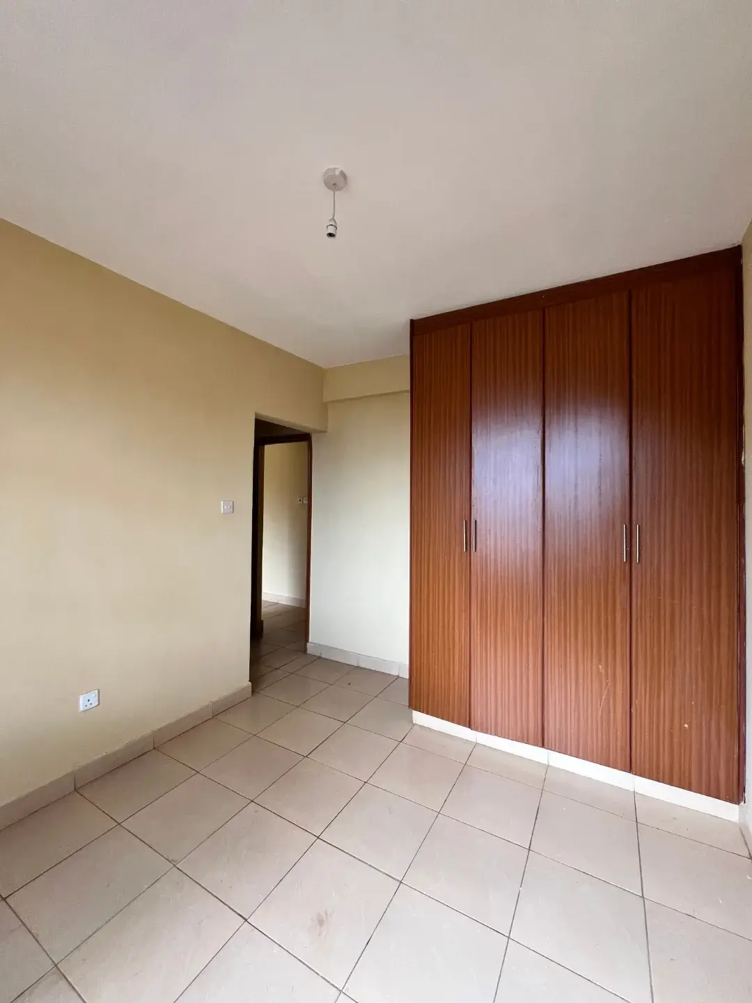 Empty bedroom with wooden wardrobe and tiled floor