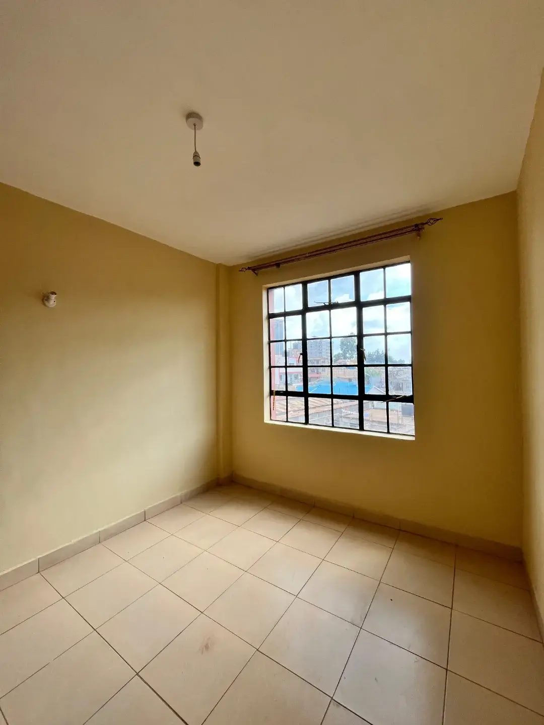Empty bedroom with yellow walls and tiled flooring