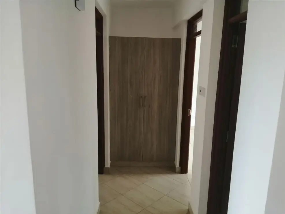 Narrow hallway with wooden doors and neutral tiling