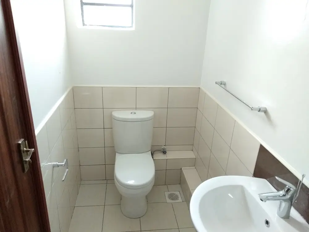 Compact bathroom with toilet, sink, and tiled walls