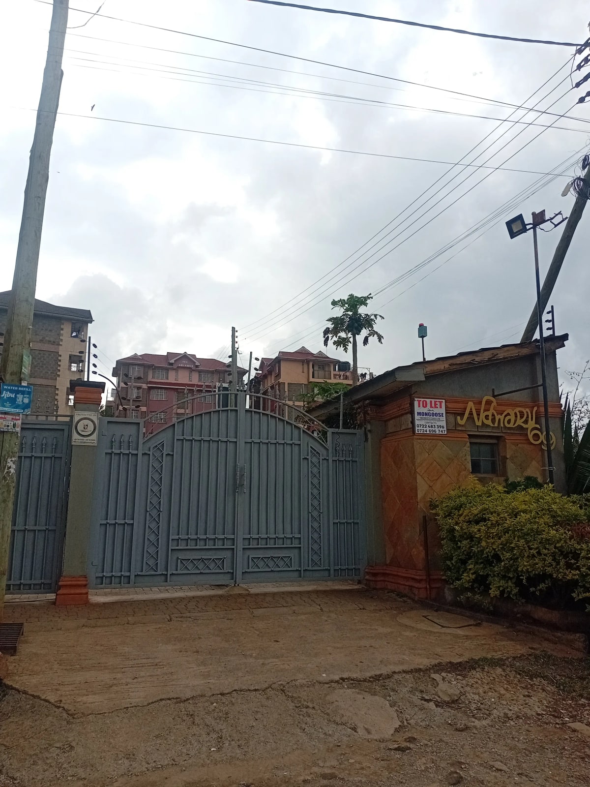 Compound entrance with blue metal gate and perimeter fence