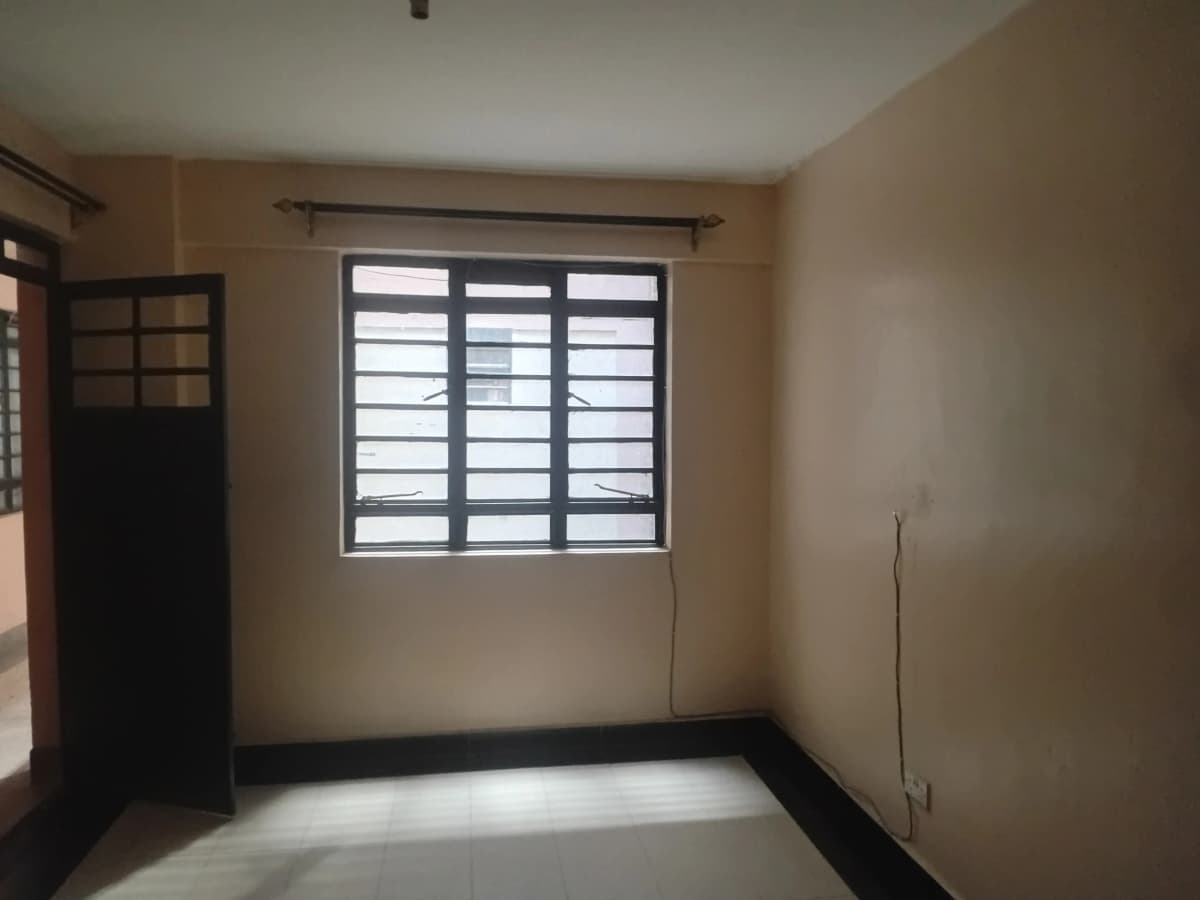 Empty bedroom with louvered window and black door frame