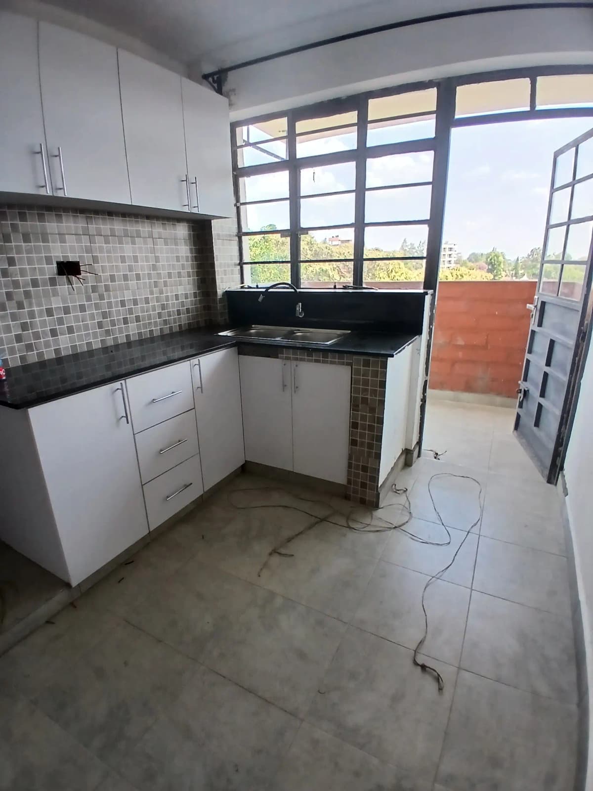 Modern kitchen with white cabinetry, black countertop, tiled backsplash
