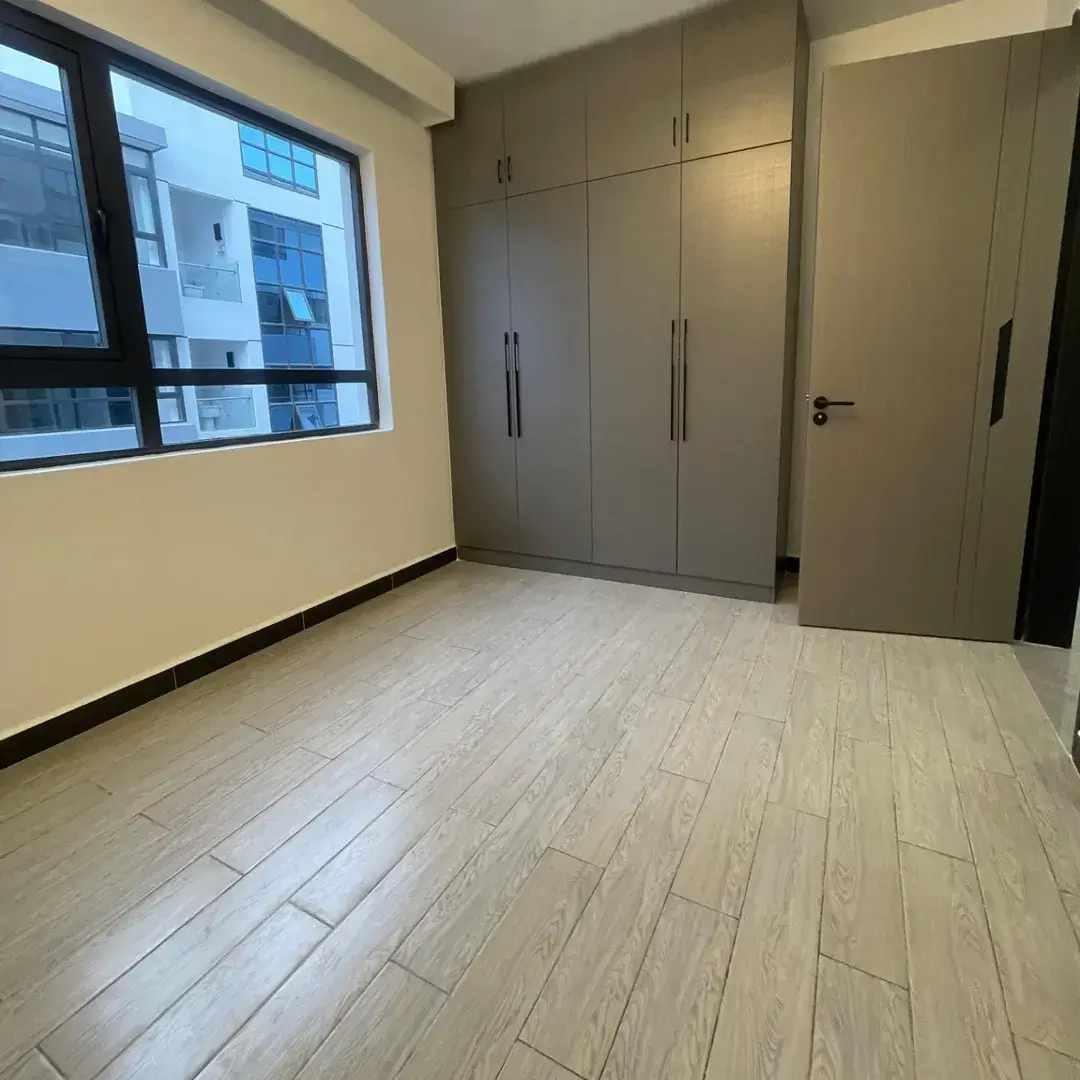 Empty bedroom with built-in wardrobes and wooden flooring