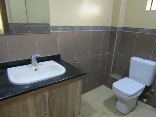 Modern bathroom with curved sink, toilet, and tiled walls