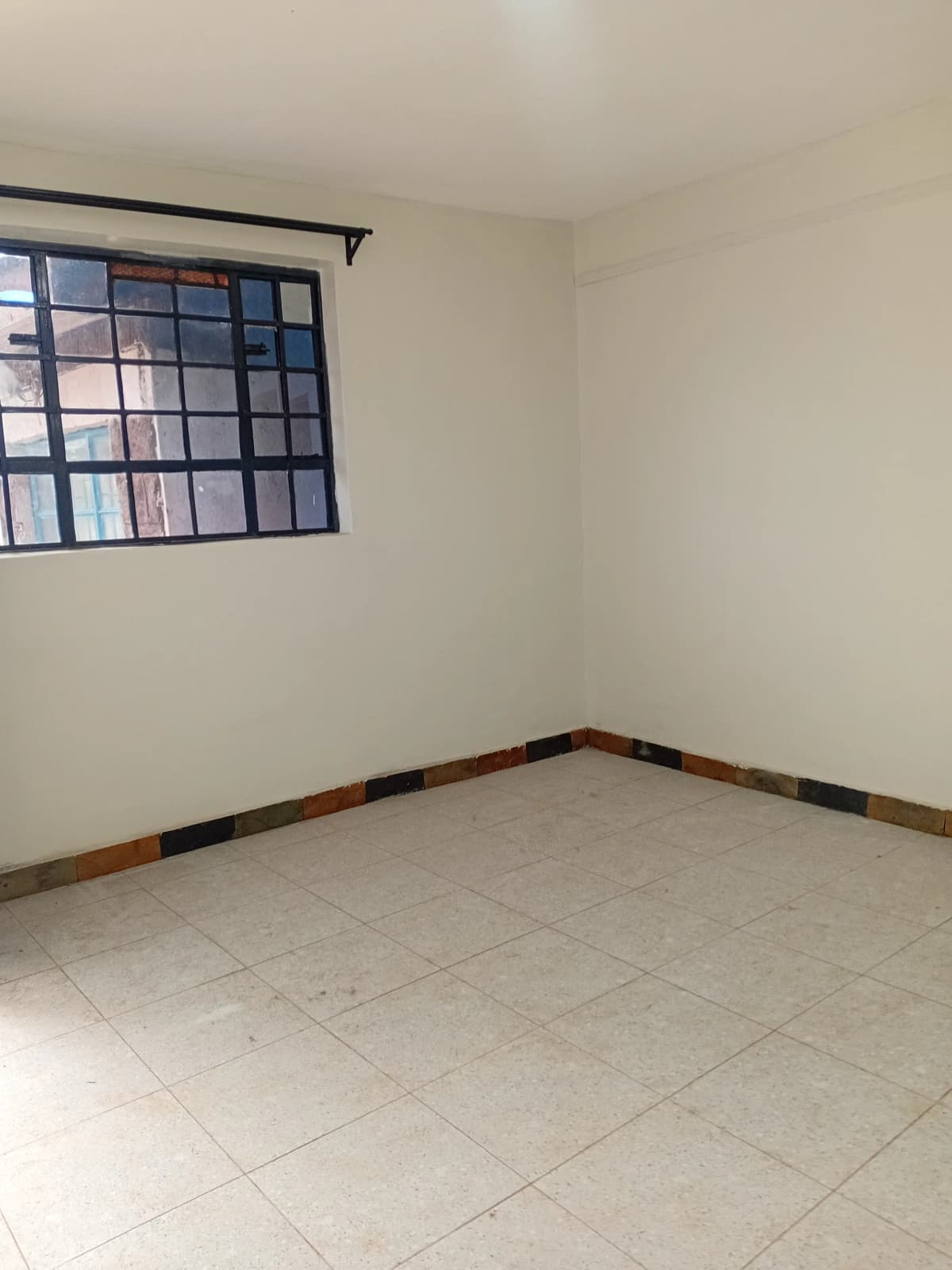 Empty bedroom with tiled floor and barred window