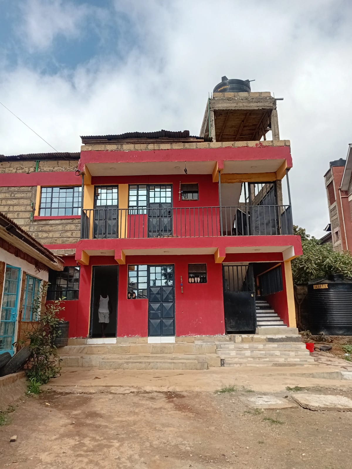 Red multi-story residential building with compound entrance