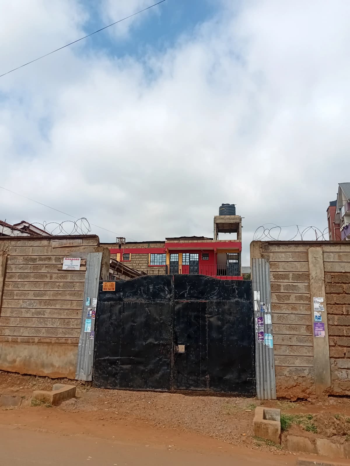 Compound entrance with black metal gate and brick walls