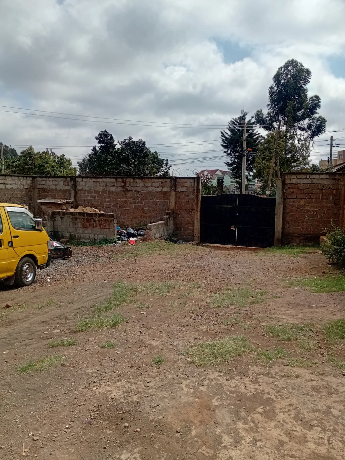 Compound entrance with brick walls and black metal gate