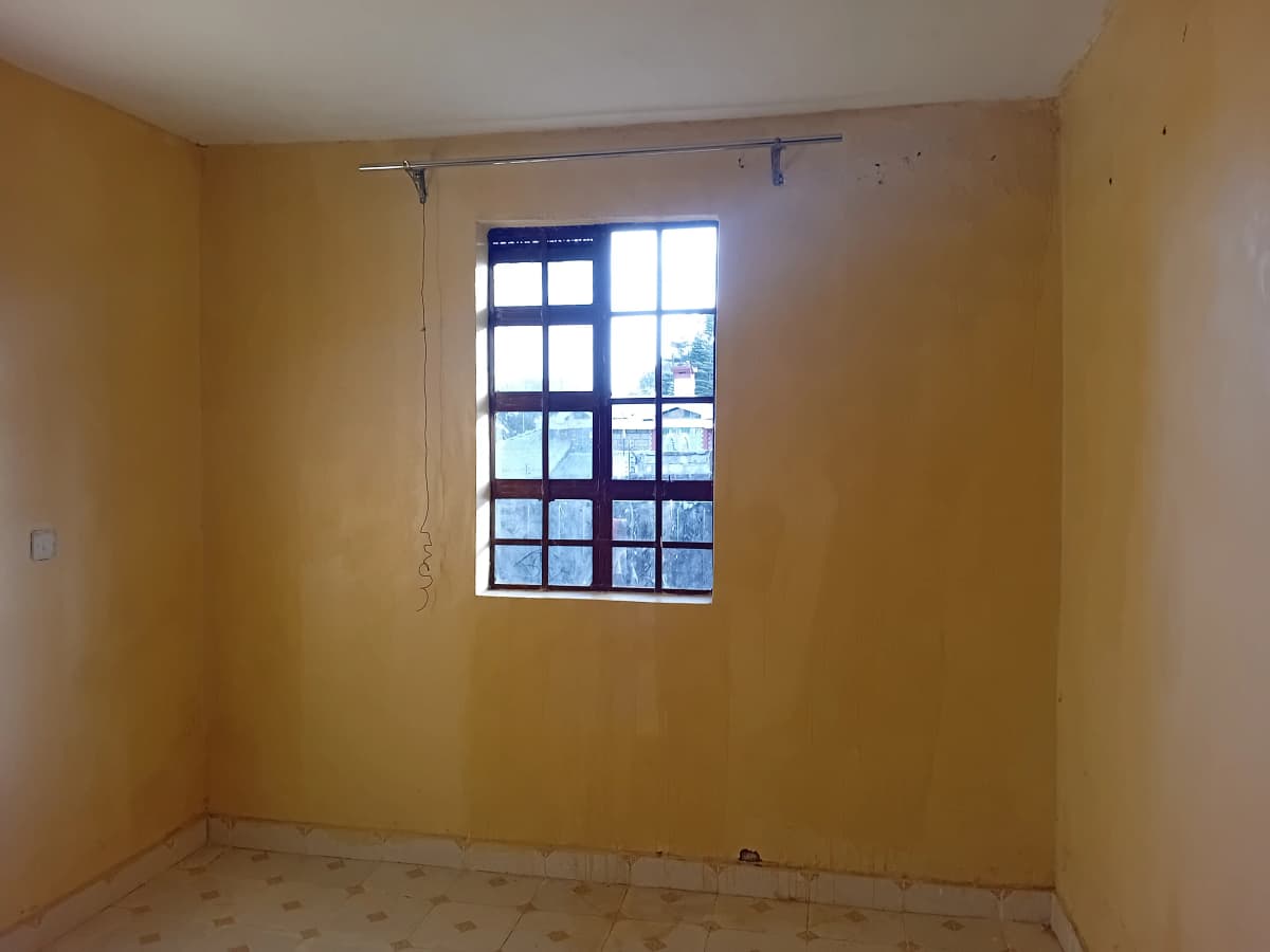 Empty bedroom with large window and yellow walls