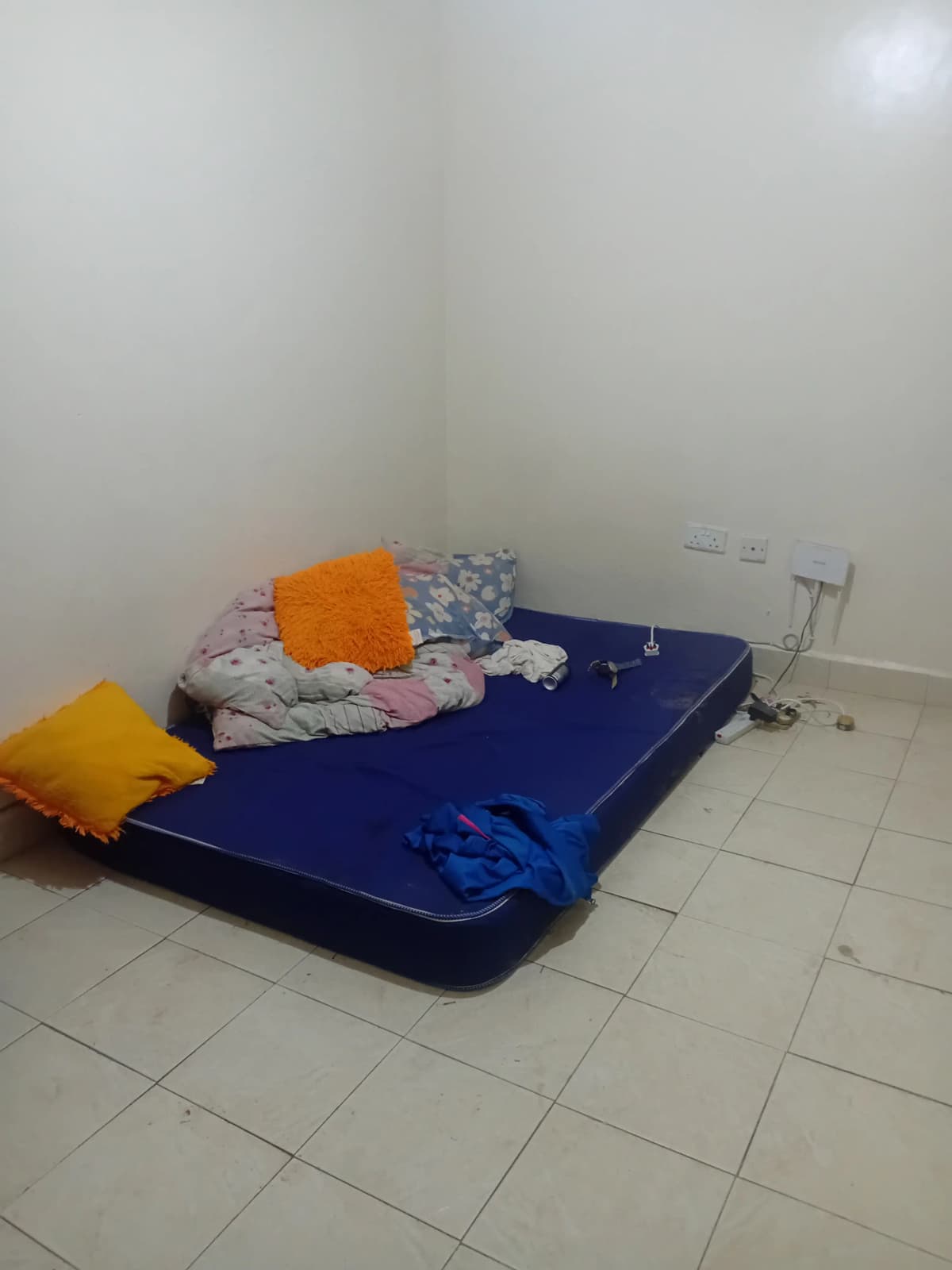 Unfurnished bedroom with blue mattress and scattered cushions