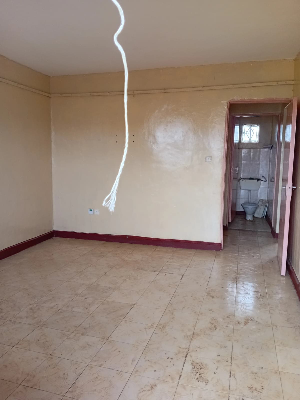 Empty living room with tiled flooring and basic fixtures