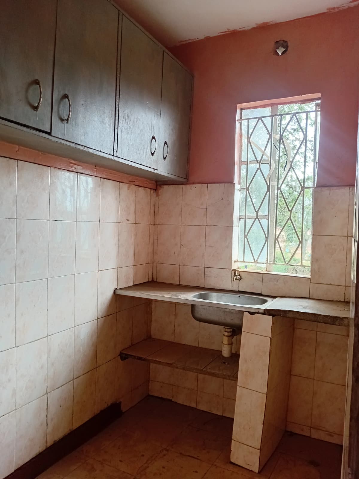 Compact kitchen with overhead cabinets, tiled backsplash, single sink