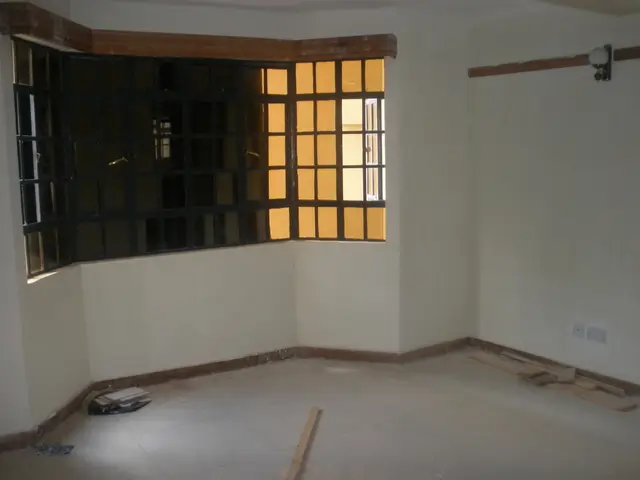 Empty living room with barred window and concrete flooring