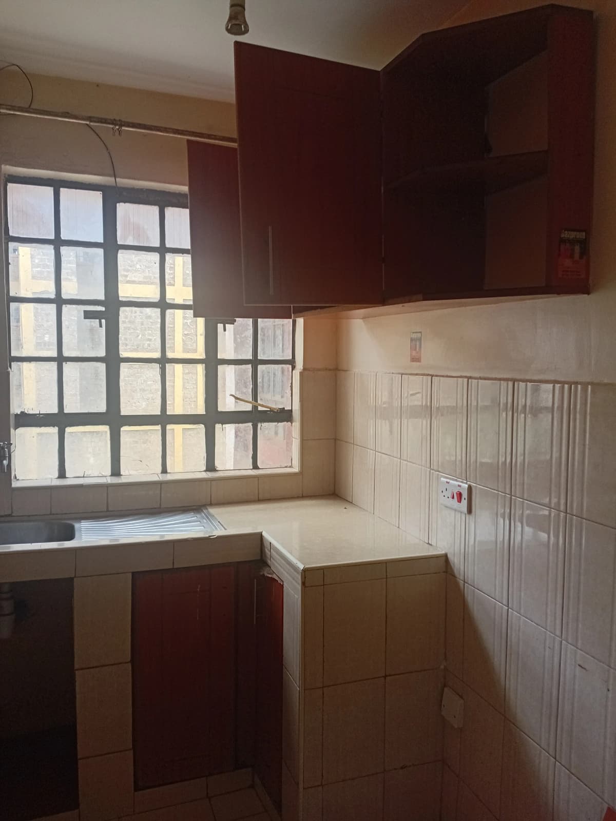 Compact kitchen with burgundy cabinets and tiled walls
