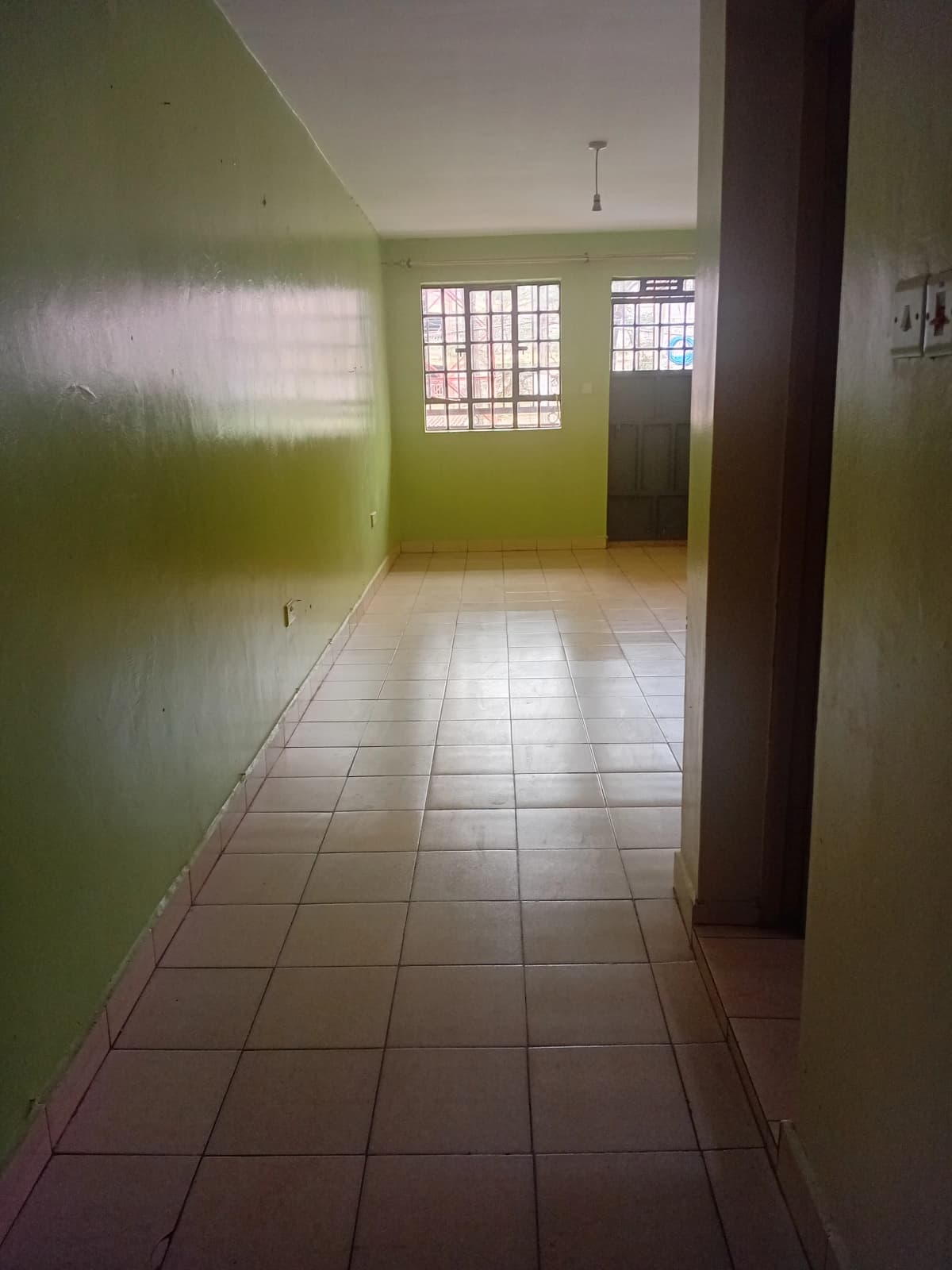 Long corridor with green walls and tiled flooring