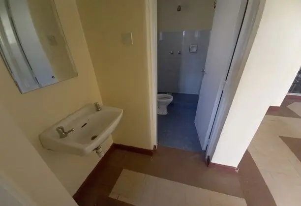 Bathroom with wall-mounted sink and blue-tiled floor area