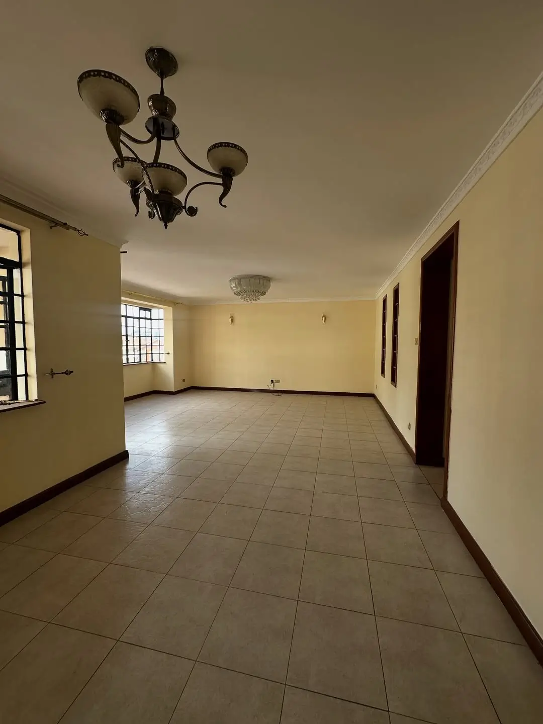 Spacious empty living room with tiled flooring and natural light