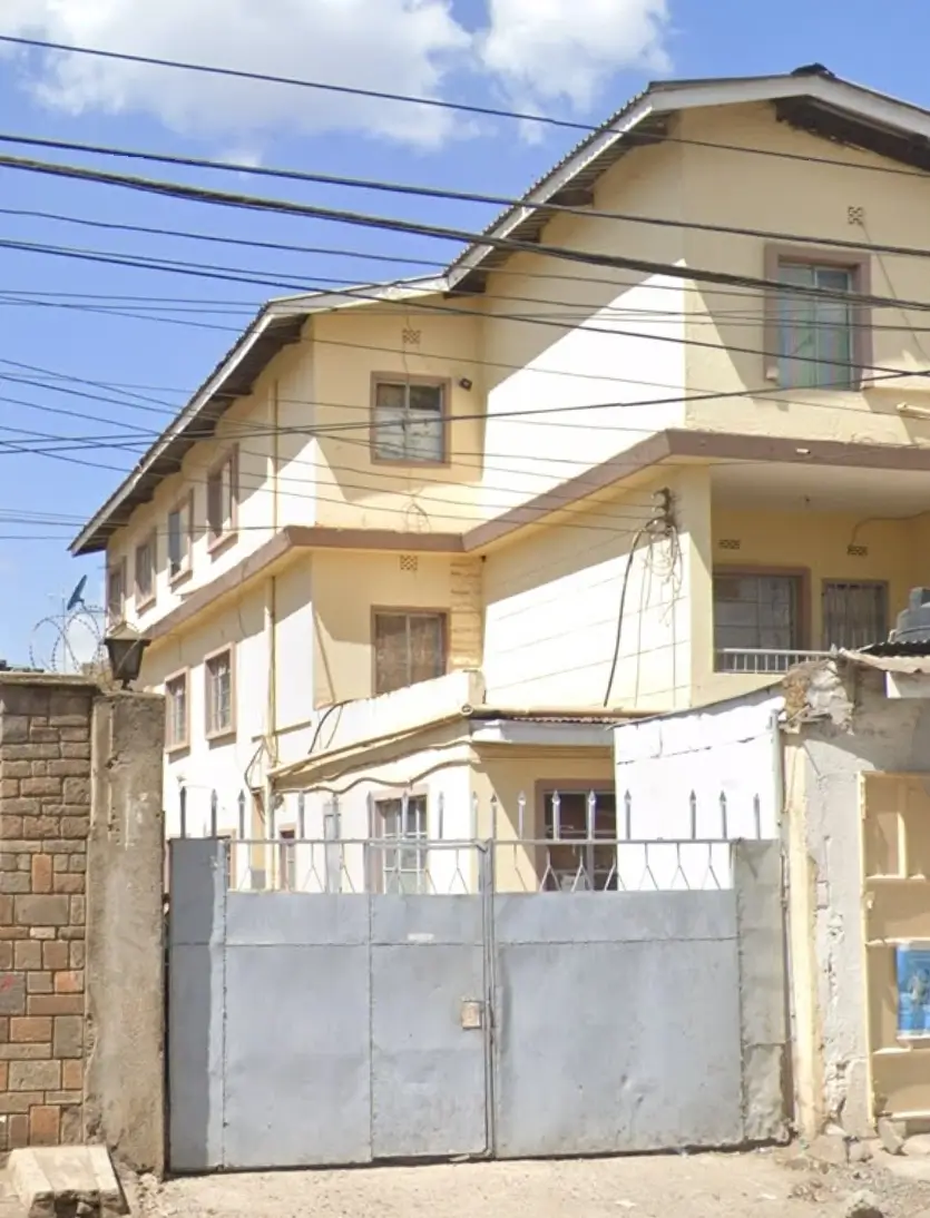 Multi-story residential building with yellow facade and metal gate