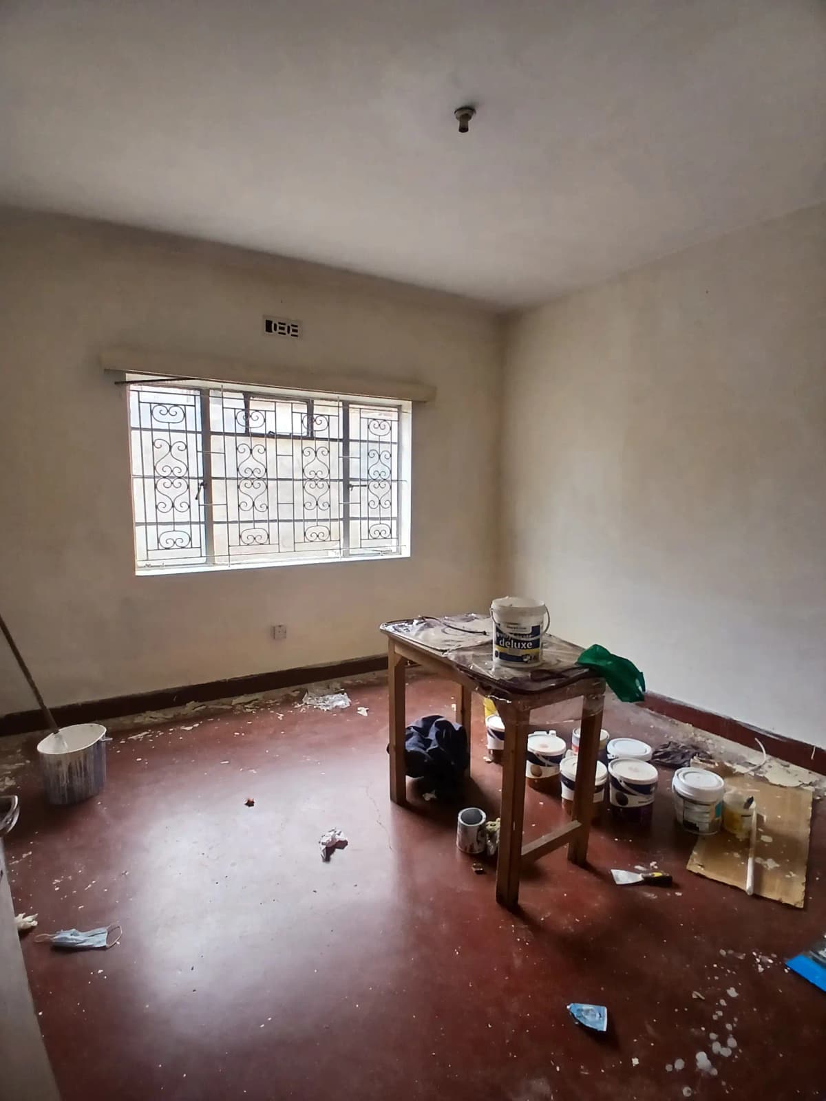 Unfurnished bedroom with barred window and red tiled floor