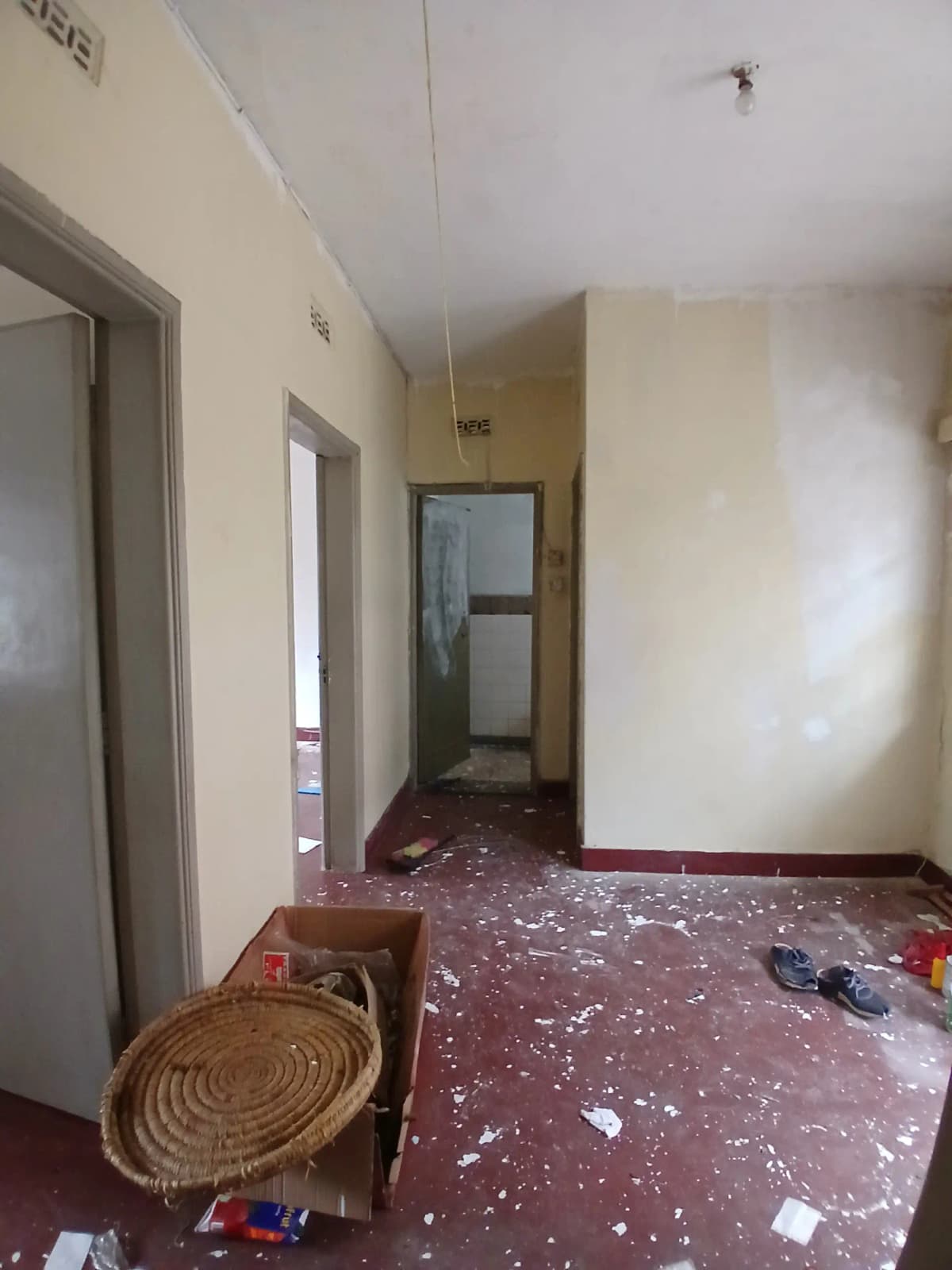 Long corridor with multiple doors, cluttered floor