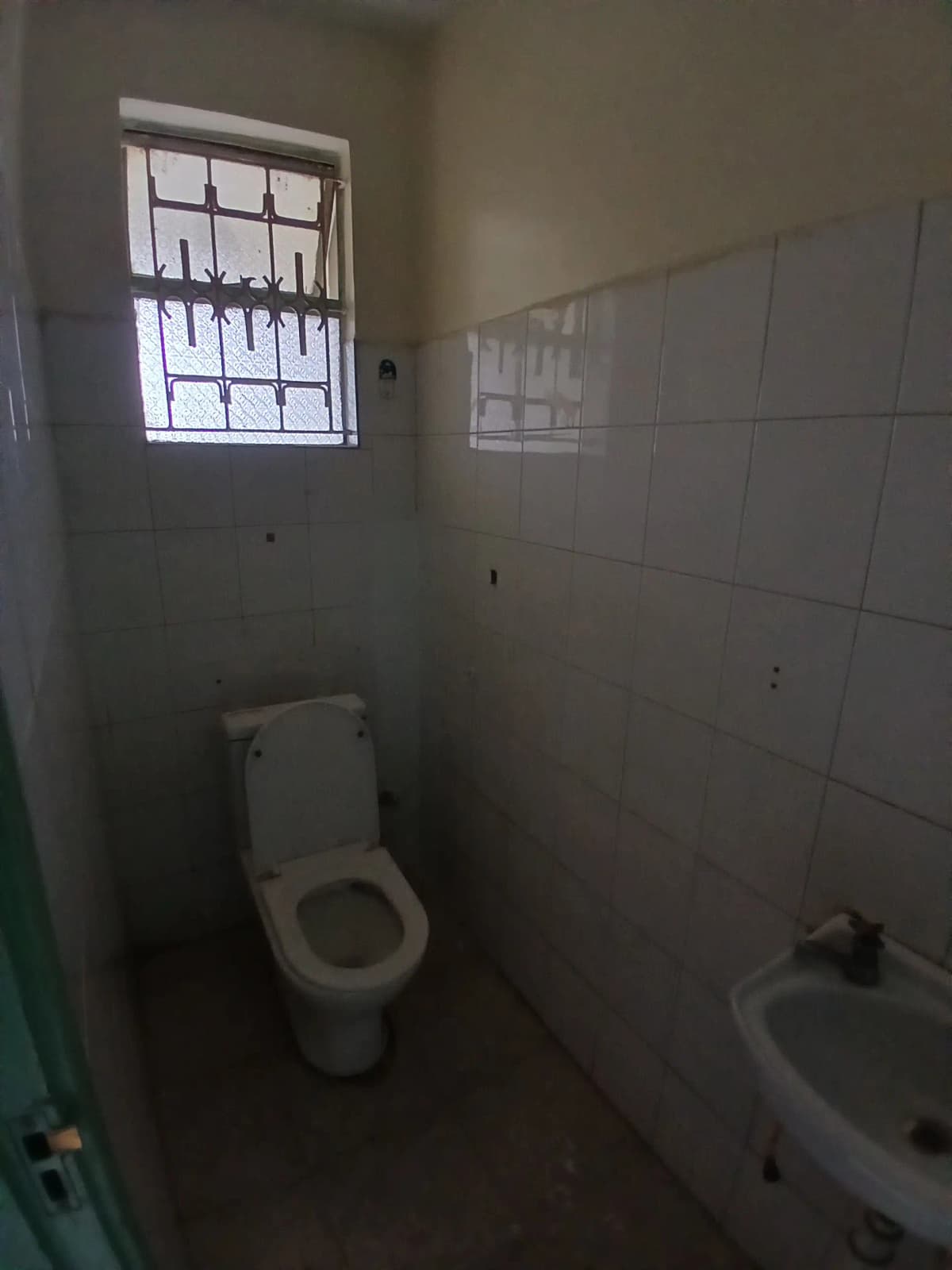 Small bathroom with toilet, sink, and barred window