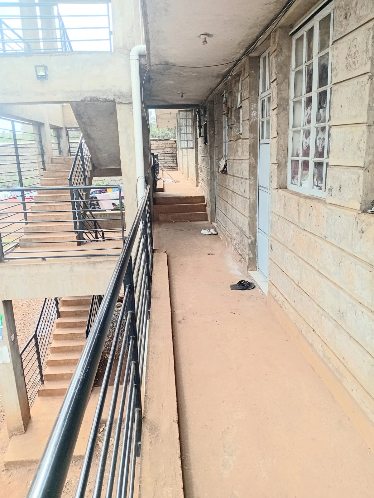 Long covered balcony with metal railings and stone walls
