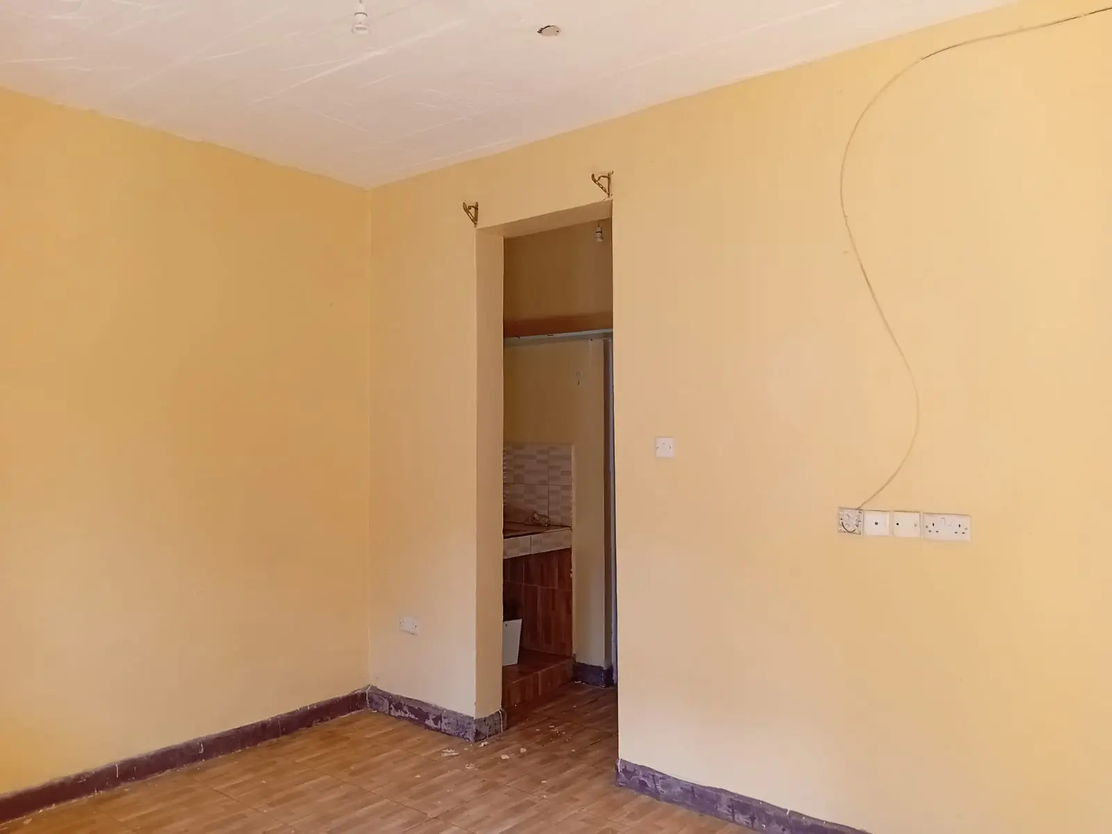Empty bedroom with yellow walls and wooden flooring