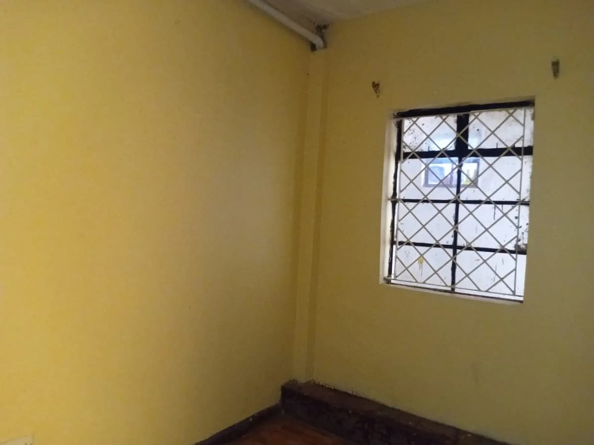 Compact bedroom with yellow walls and barred window