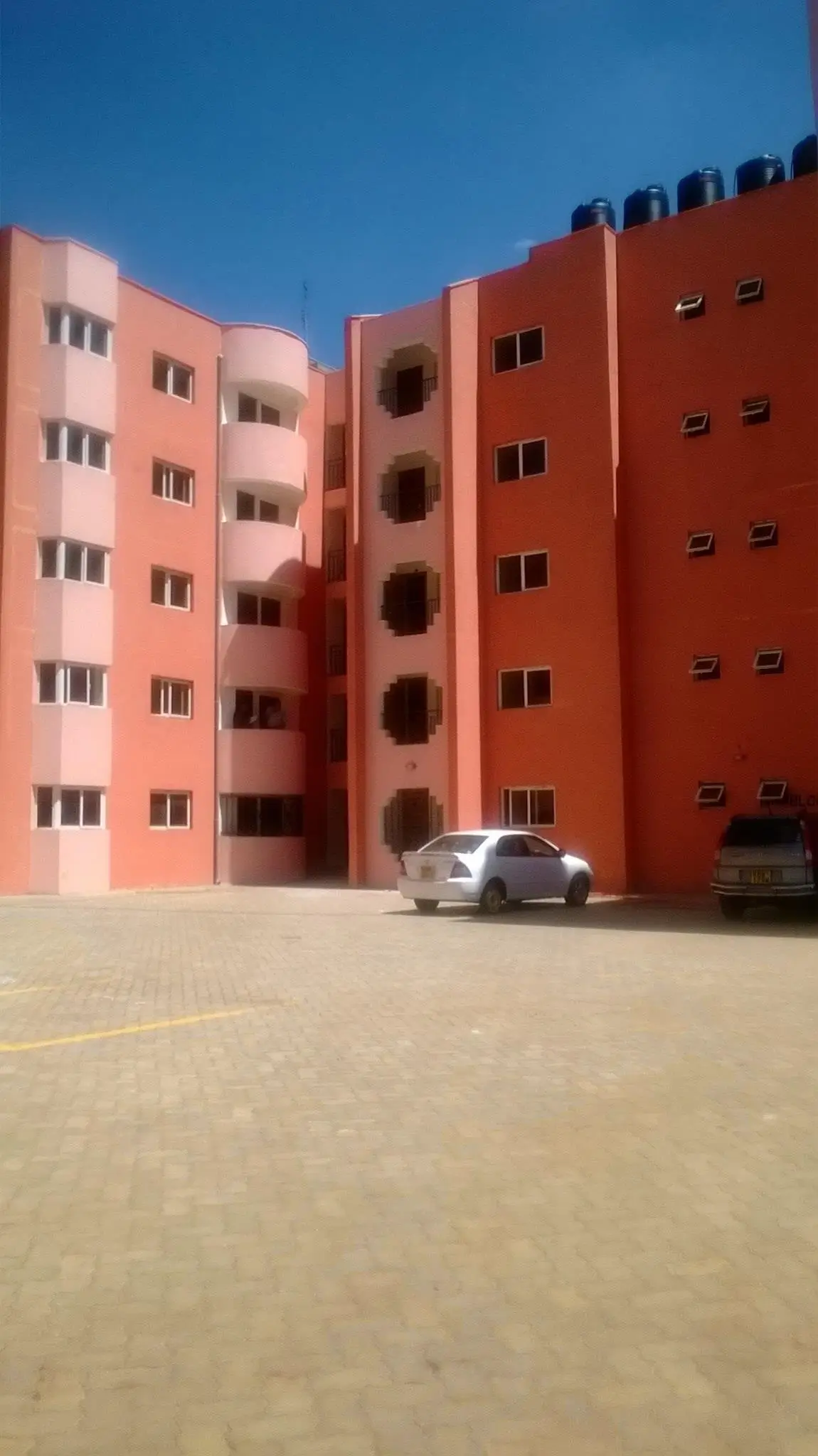 Modern red-brick apartment building with ground-level parking