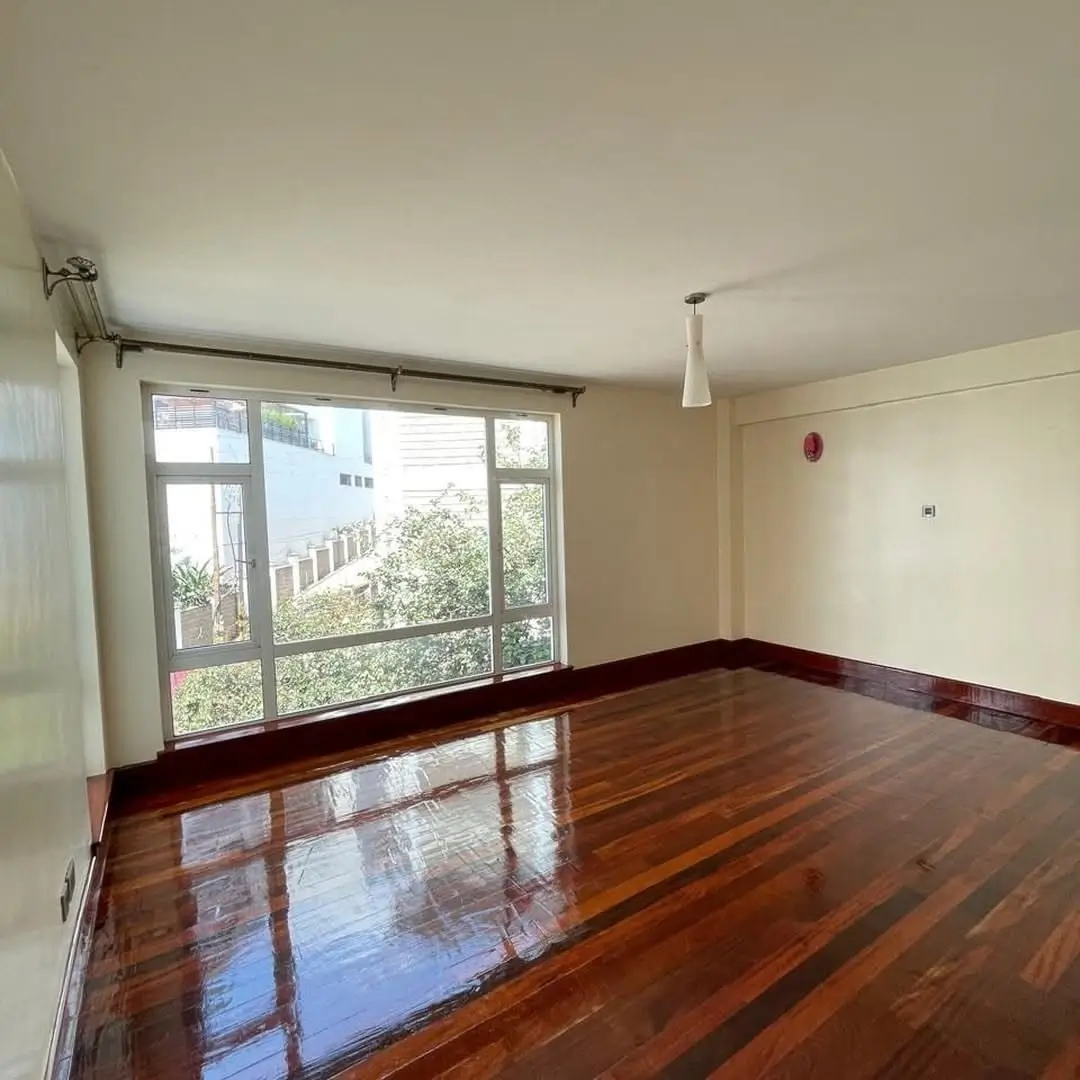 Spacious living room with polished wooden floors and large windows