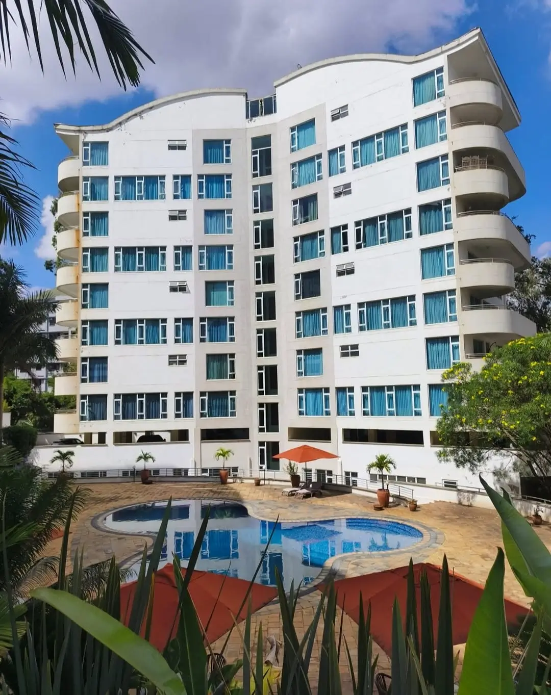 Modern residential building with curved balconies and pool grounds