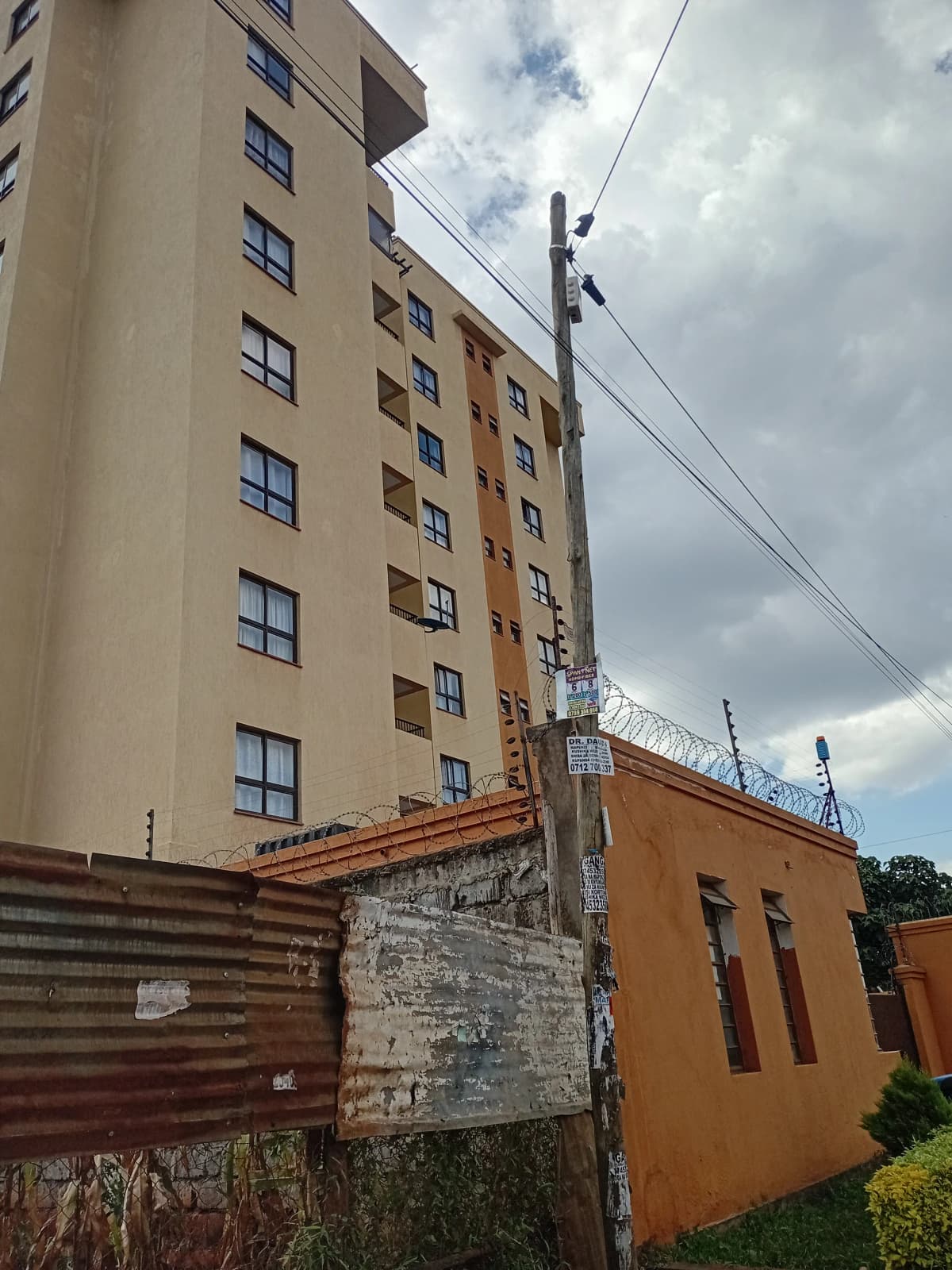 Multi-story residential building facade with surrounding compound structures